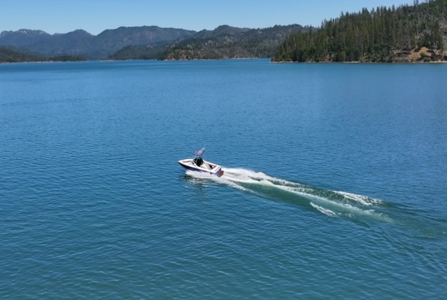 Centurion T-5 wakeboard boat speeding across open water on Shasta Lake viewed from above at Silverthorn Resort