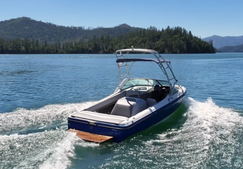 Centurion T-5 wakeboard boat cruising on Shasta Lake with forested mountain shoreline at Silverthorn Resort
