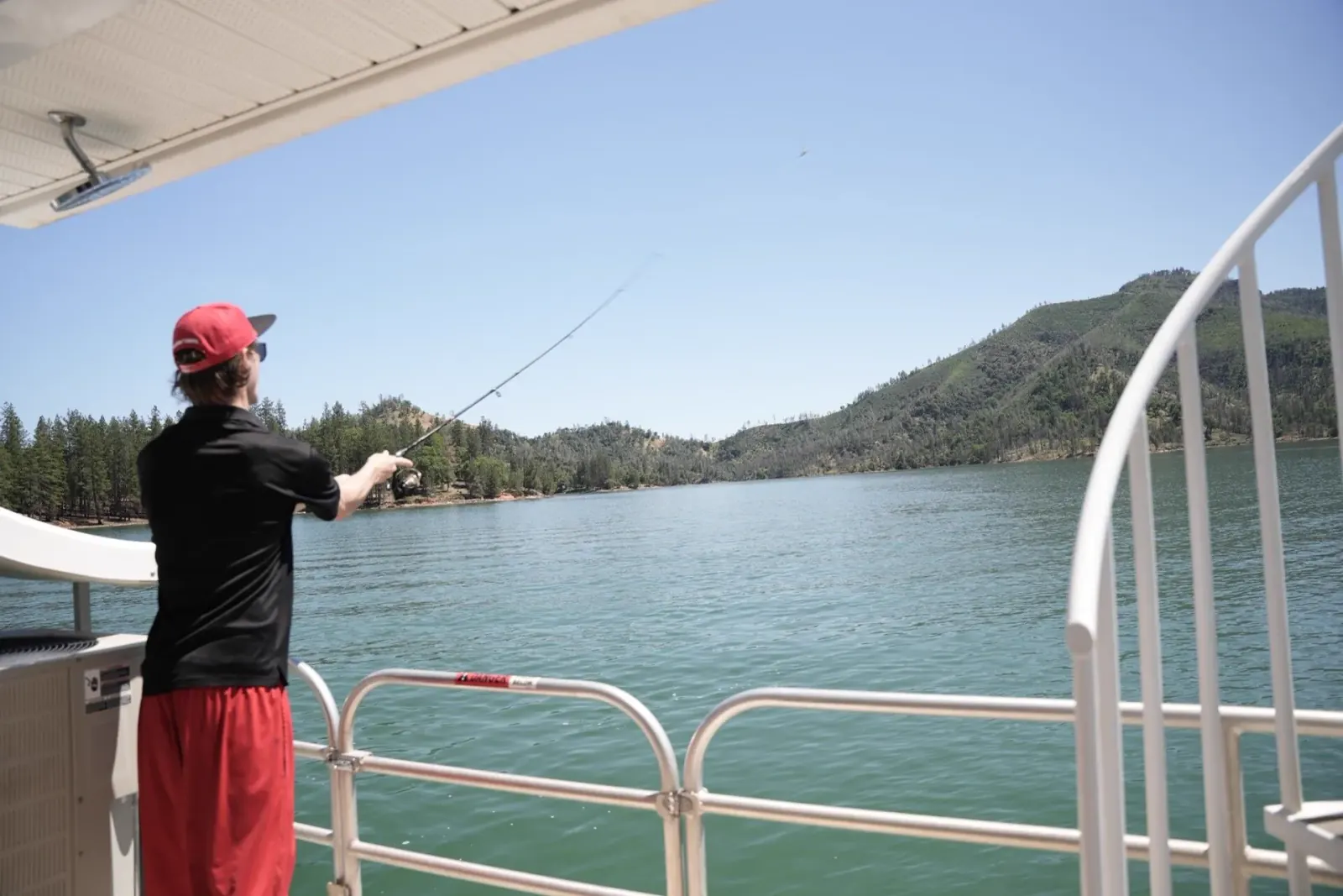 Fishing rod casting toward Shasta Lake from a houseboat deck