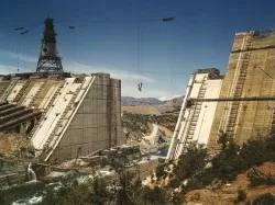 Color photograph of Shasta Dam mid-construction with cableways and concrete forms