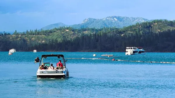 Boaters and houseboats cruising the calm waters of the Squaw Creek Arm of Shasta Lake