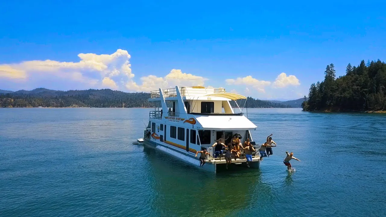 Friends jumping off a Silverthorn houseboat into Shasta Lake on a warm California summer day