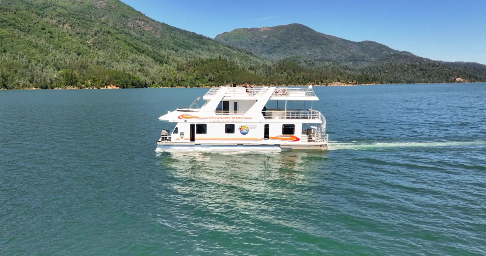 Queen luxury houseboat cruising on Shasta Lake with mountain backdrop