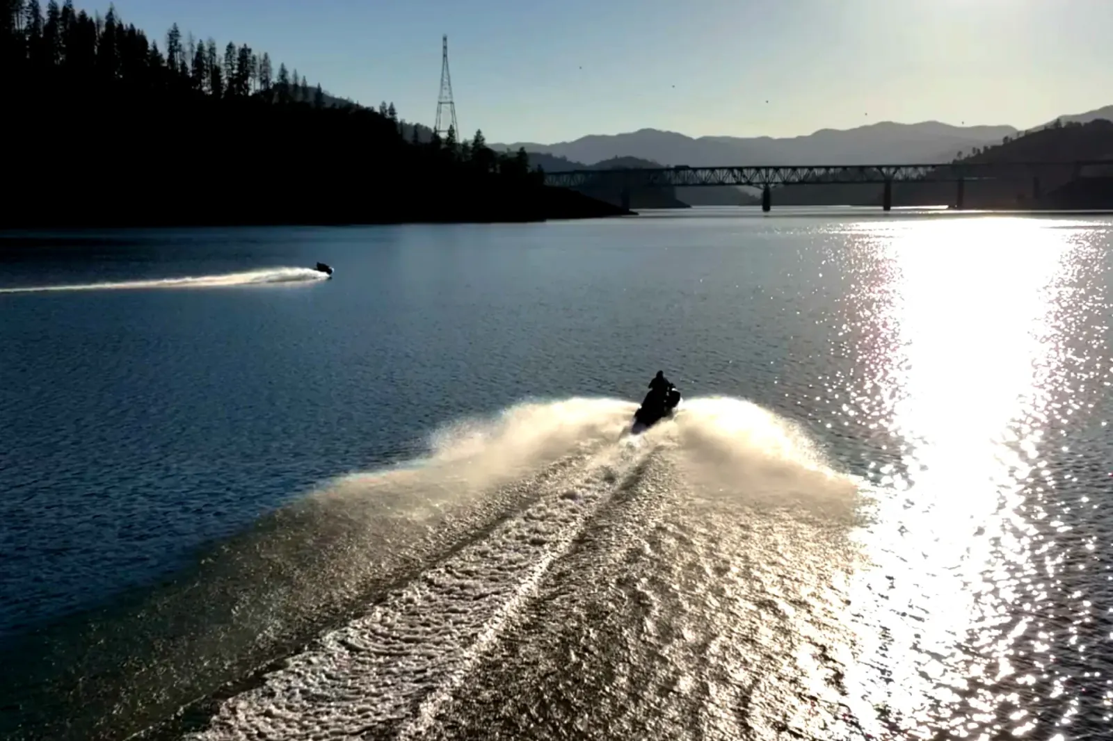 Aerial drone view of a jet ski carving wake patterns on the calm waters of Shasta Lake