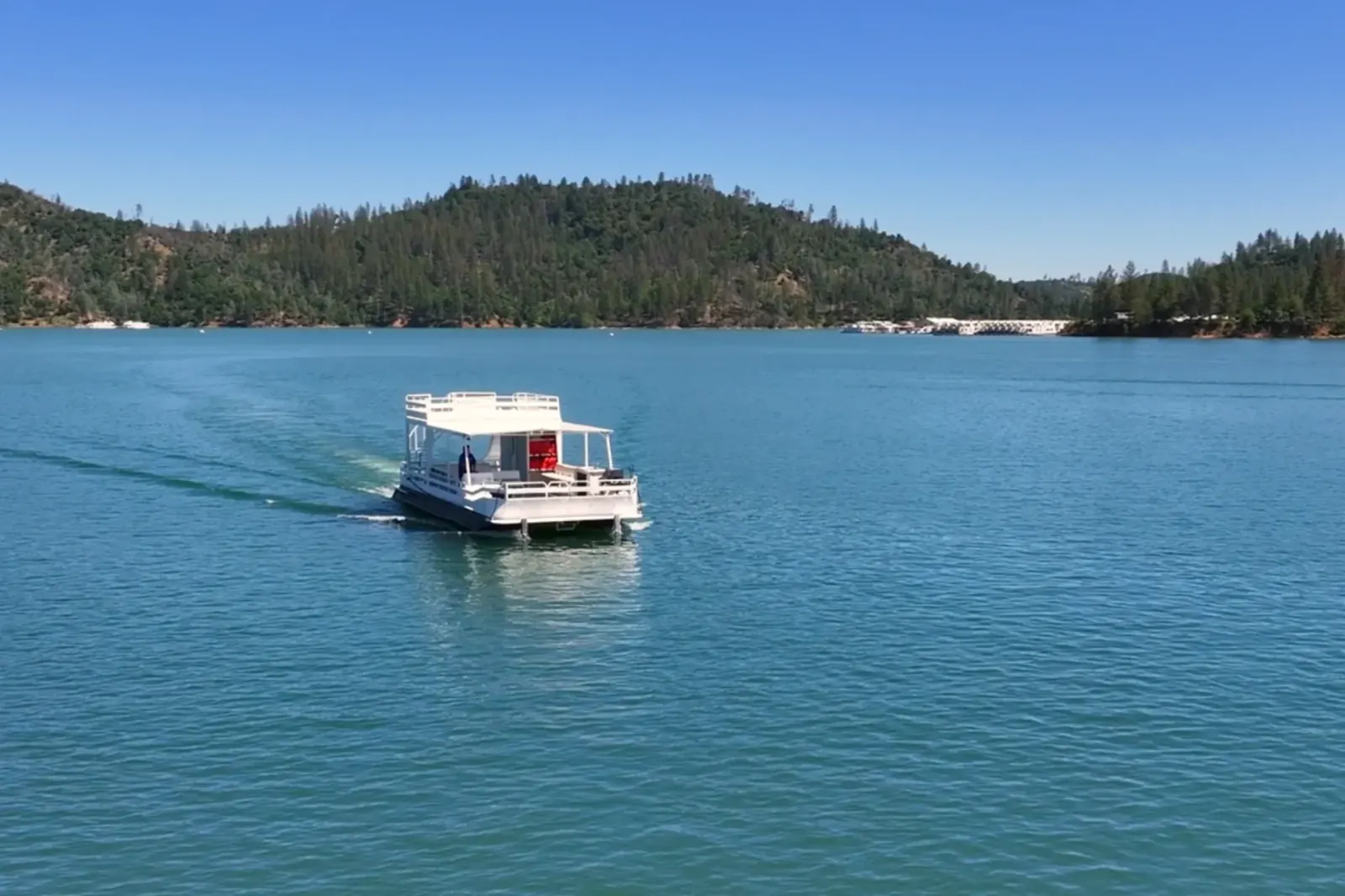 Party Cruiser I cruising in the distance on Shasta Lake with mountain backdrop