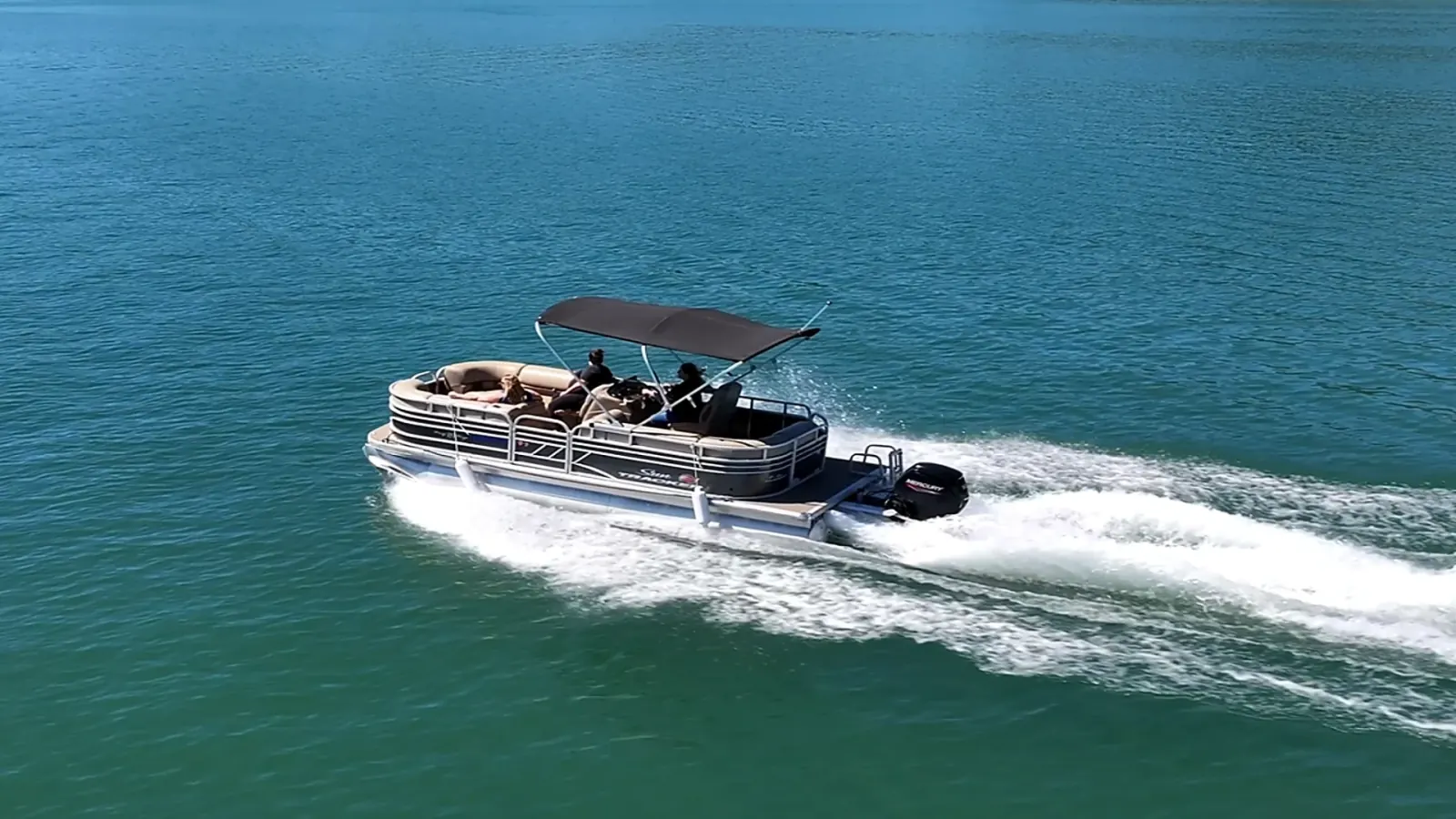 Aerial drone view of Sun Tracker Pontoon creating wake on open Shasta Lake waters