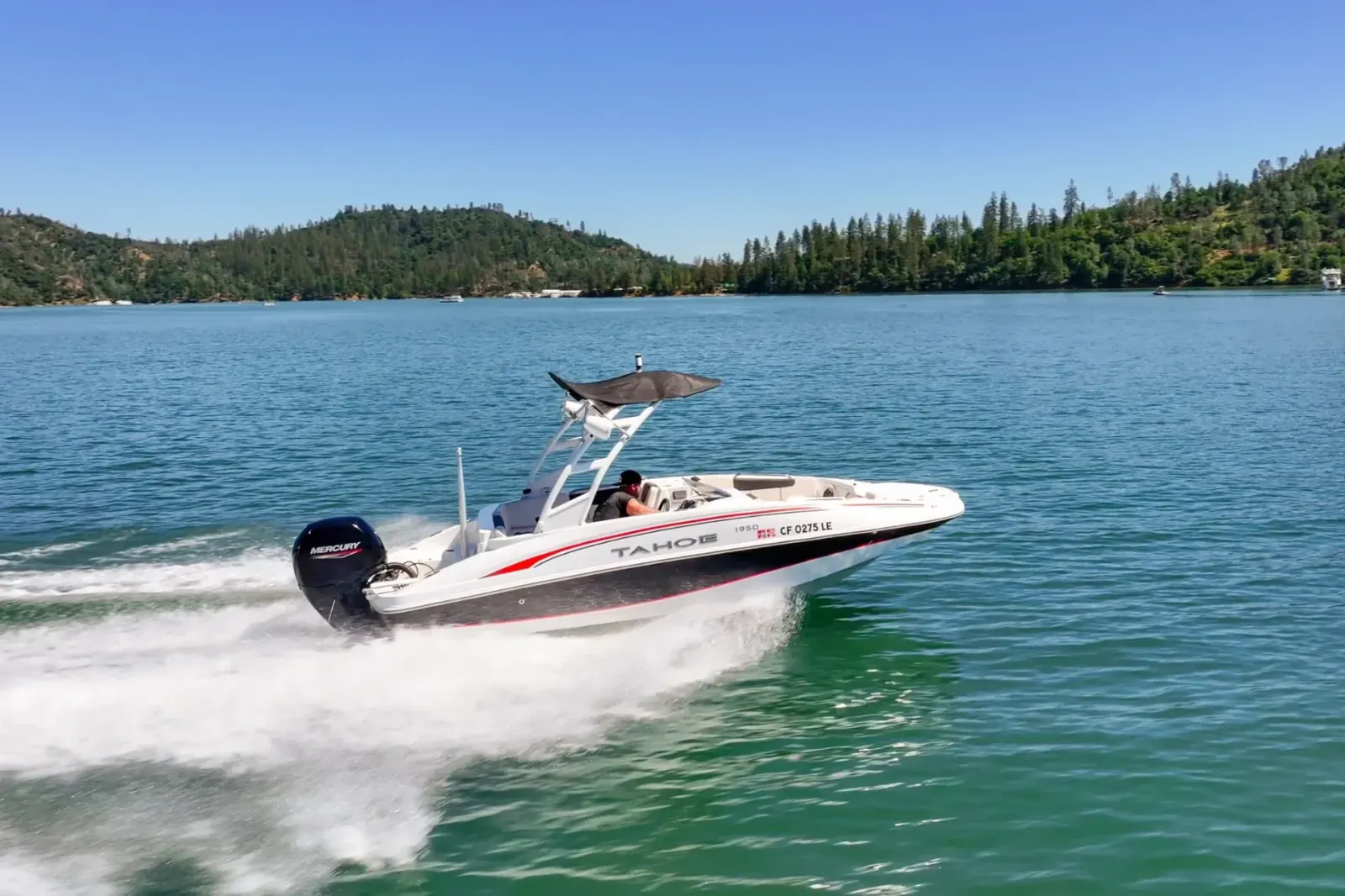 Tahoe Deck Boat 150 at full speed cruising on Shasta Lake with forested hills