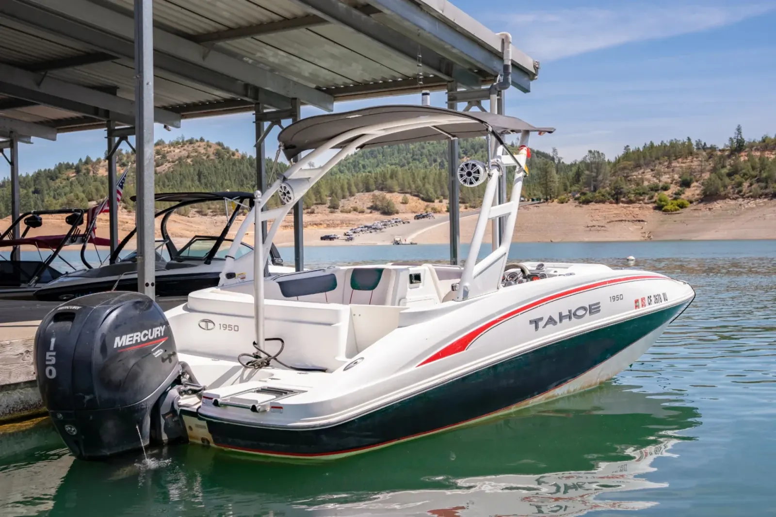 Tahoe Deck Boat 150 side profile with bimini top docked at Silverthorn Resort marina